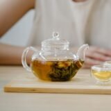 Ibric de cupru și două cești mici cu cafea cu spumă, servite pe o tavă alături de pahare cu apă