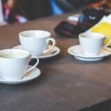 Mai multe cești de cafea goale pe o masă de lemn, sugerând un consum mare de cafea pe parcursul zilei